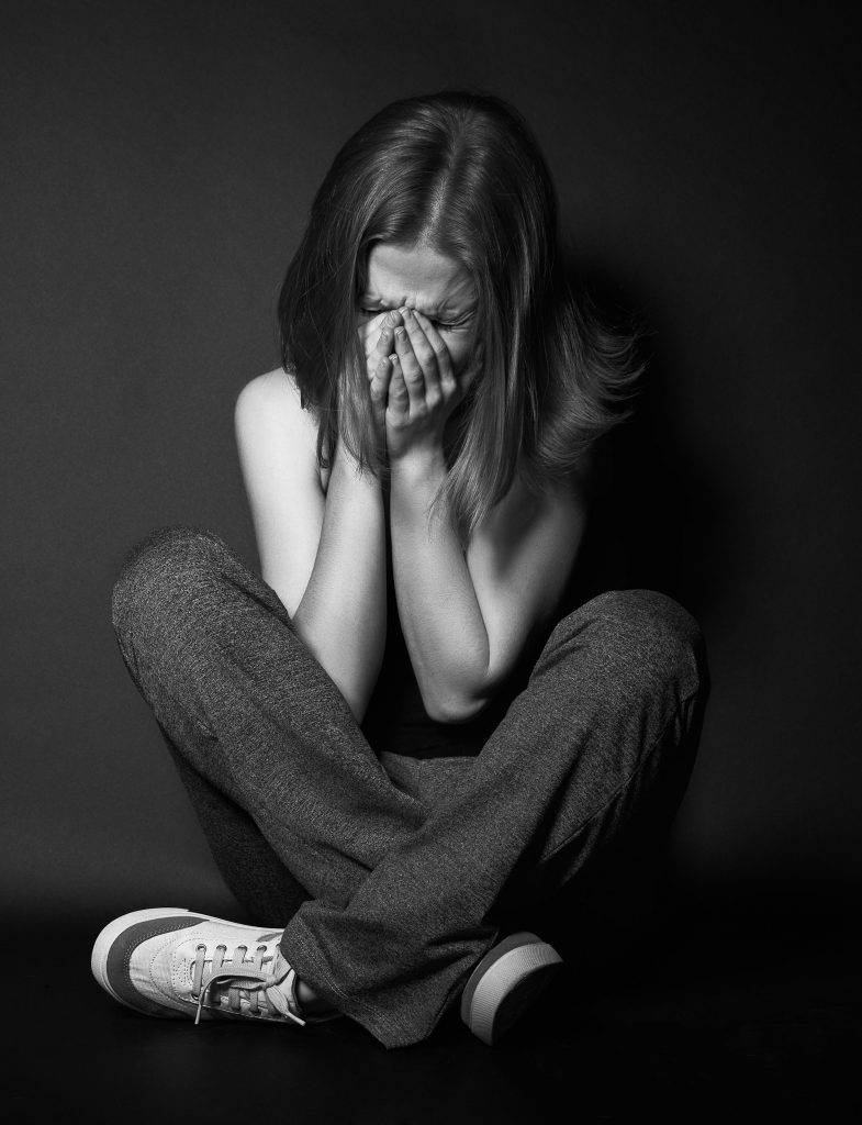 Frau mit Depressionen in sitzender Haltung und Gesicht in den Händen