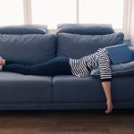 Eine Frau, die Pause macht auf dem Sofa, statt dringende Aufgaben zu erledigen