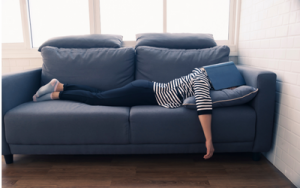 Eine Frau, die Pause macht auf dem Sofa, statt dringende Aufgaben zu erledigen