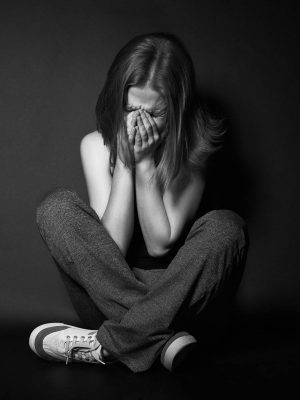 Frau mit Depressionen in sitzender Haltung und Gesicht in den Händen